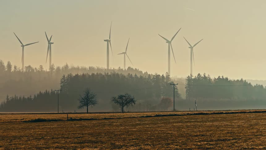 Turbines spinning on a wind farm above the trees