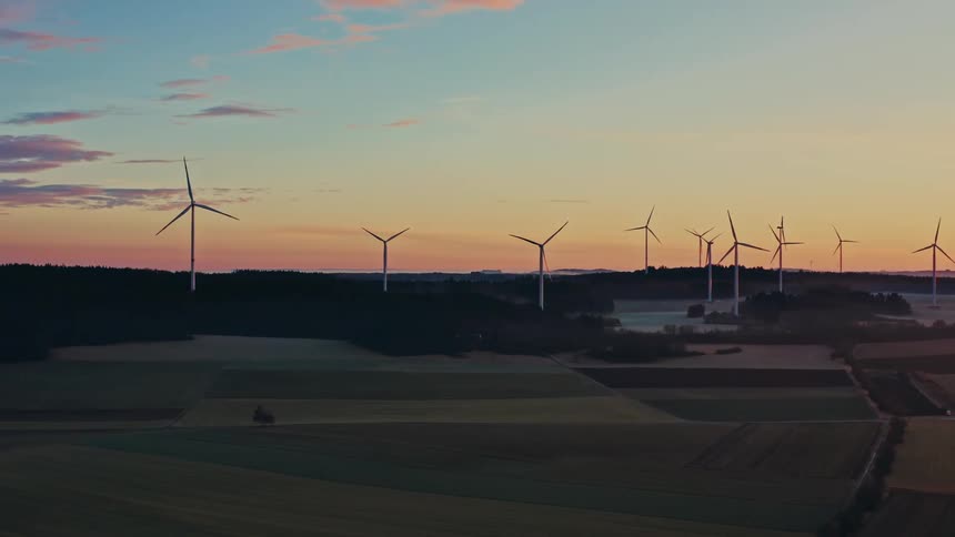 Turbines spinning on a wind farm as traffic moves on the road