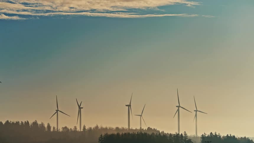 Turbines spinning on a wind farm above the trees