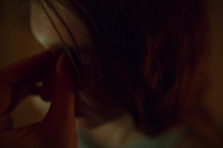 Person touches the face near the eye with a finger in a lowlight environment