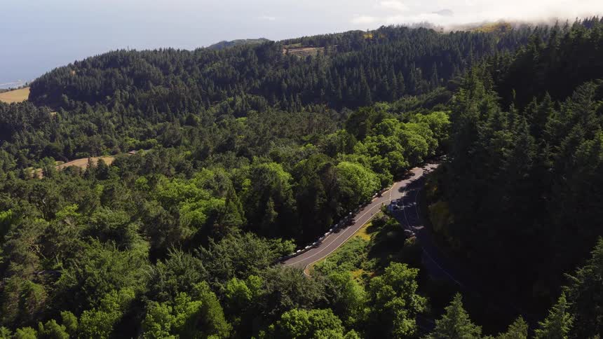 Aerial of forested mountains on a mostly sunny summer day