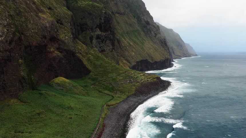 Mountains along the coast as waves roll in to shore