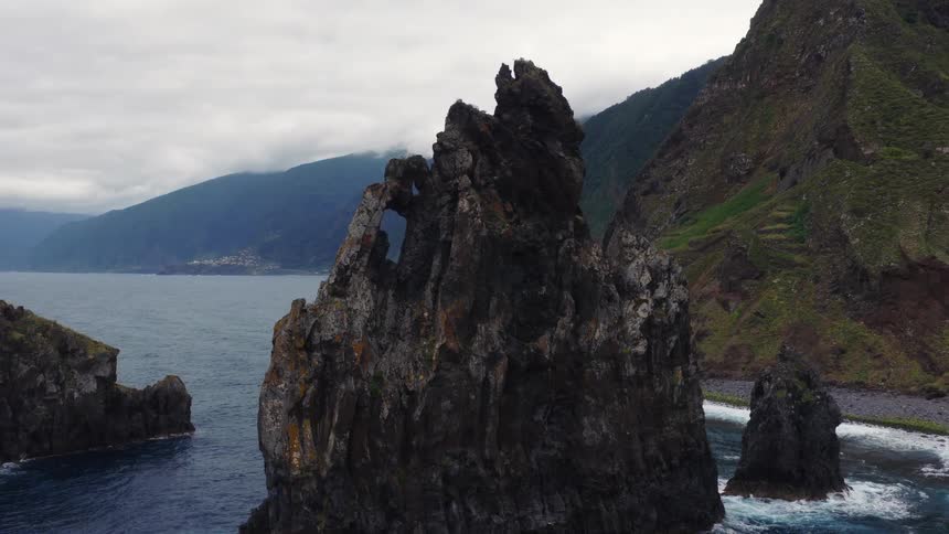 Mountains along the coast as waves splash against rock formations in the water