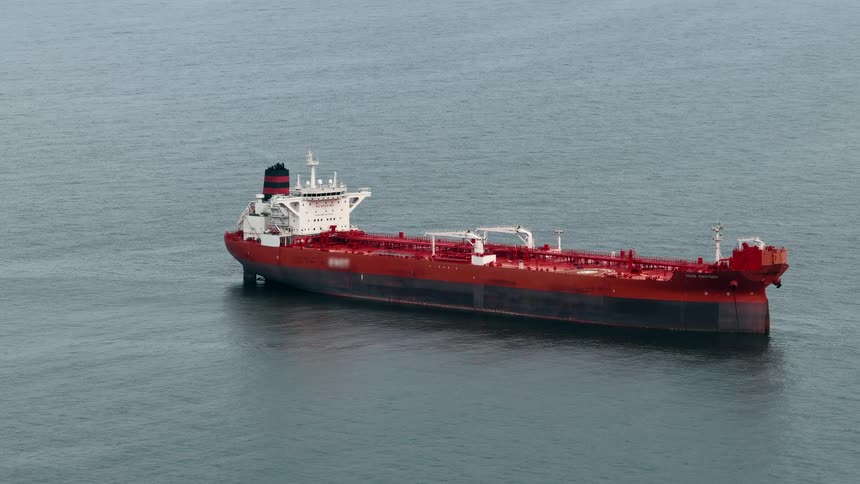 Aerial of a large red cargo ship at sea during daytime