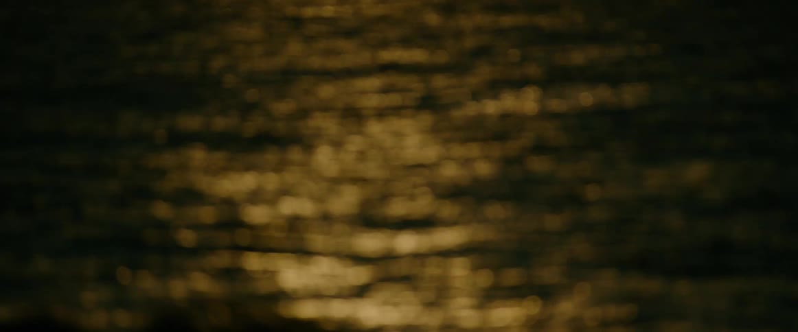 Golden reflections on a water surface out of focus in low light