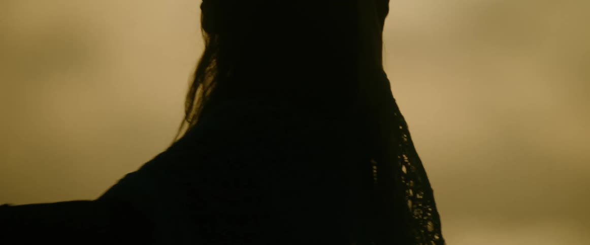 Woman partially silhouetted against an overcast sky dances