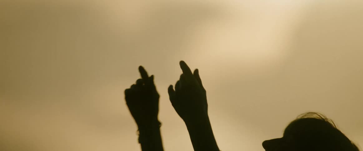 Silhouette of a person with an arm raised against a warm backlit background