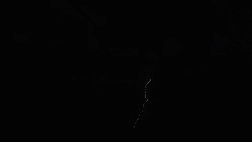 In a dark night sky bright bolts of lightning flicker and crawl across the clouds momentarily illuminating the heavy storm formations before disappearing back into the pitch black atmosphere