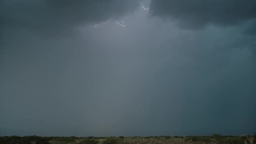 Lightning strikes the ground beneath dense clouds in an open landscape