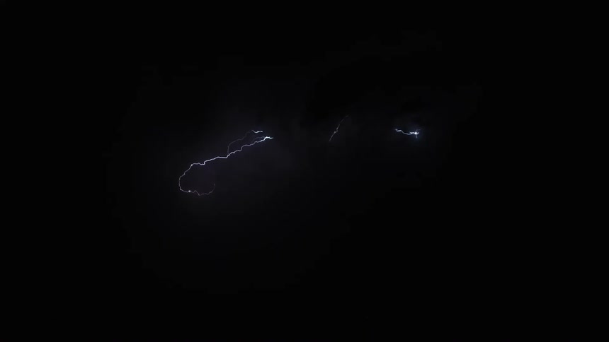 Lightning cracks across the sky illuminating storm clouds in the darkness