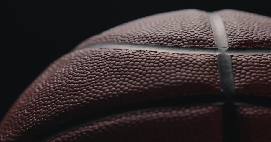 A close up of a part of a basketball orbiting against a black background