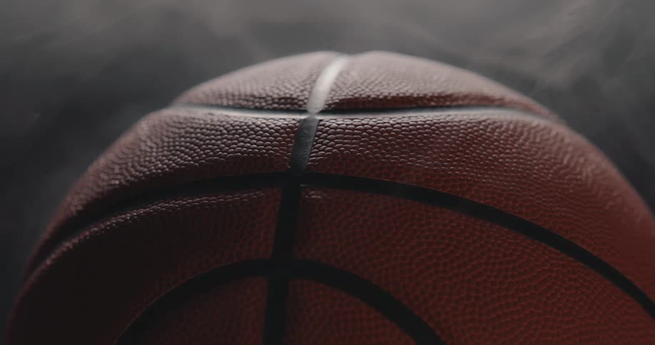 Basketball in closeup showing a pebbled texture and black seams under soft lighting