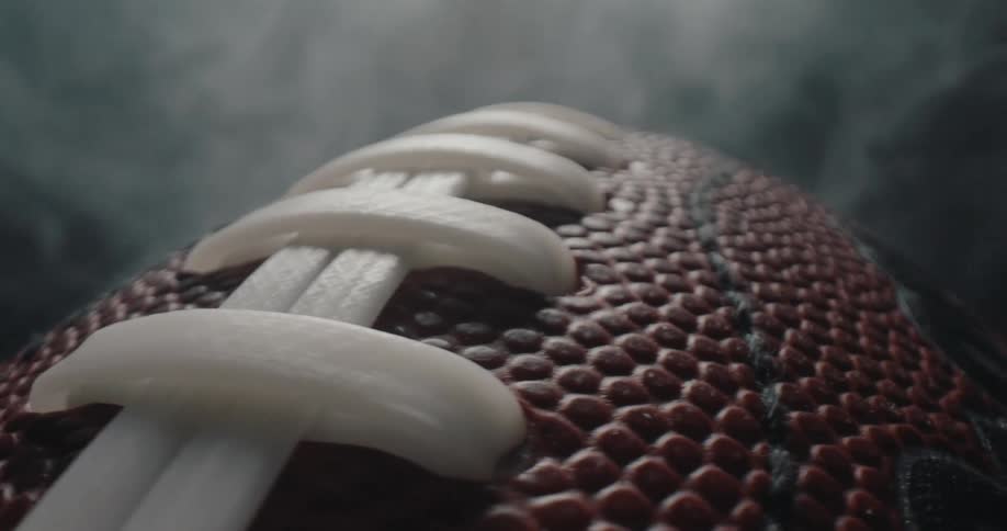 Close up of a rotating american football rotating while surrounded by vapour in a photo studio