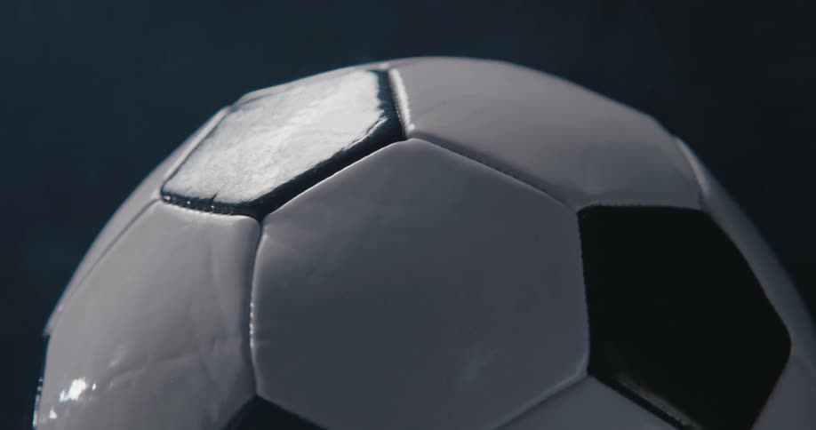Bright light reflects off a spinning soccer ball its surface catching sharp highlights as it rotates in a full 360degree motion