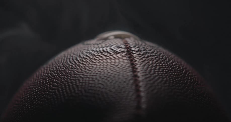 Smoke billowing around an american football against a dark background