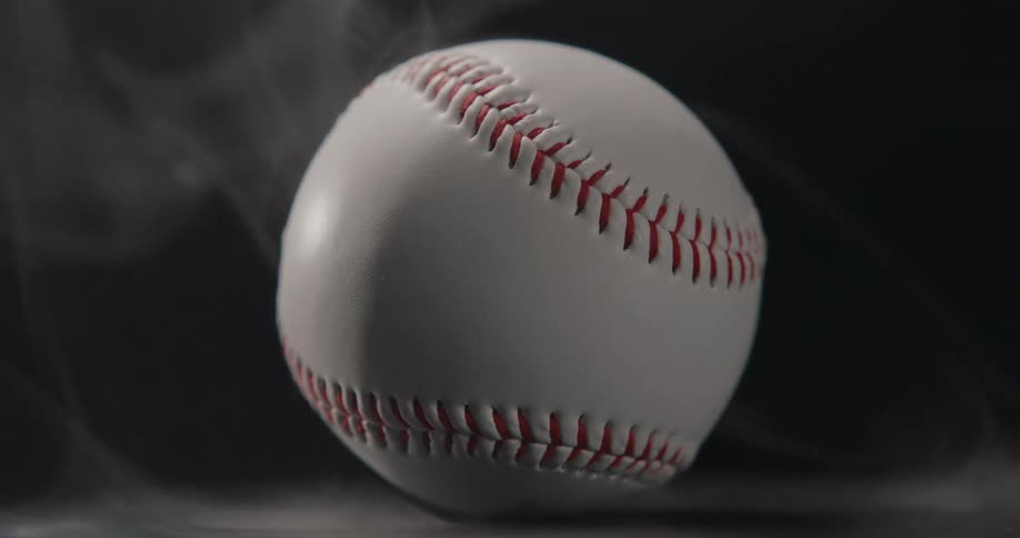 Light shines on a baseball as smoke rises