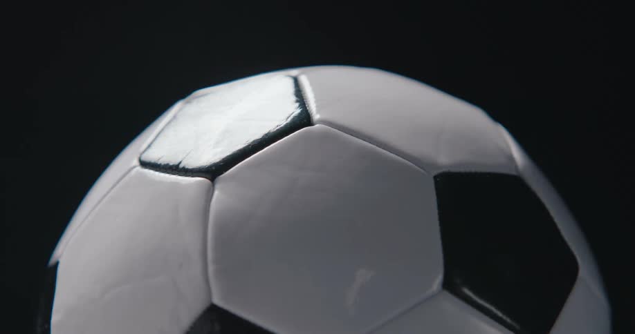 Light shines on a soccer ball as it turns and rotates
