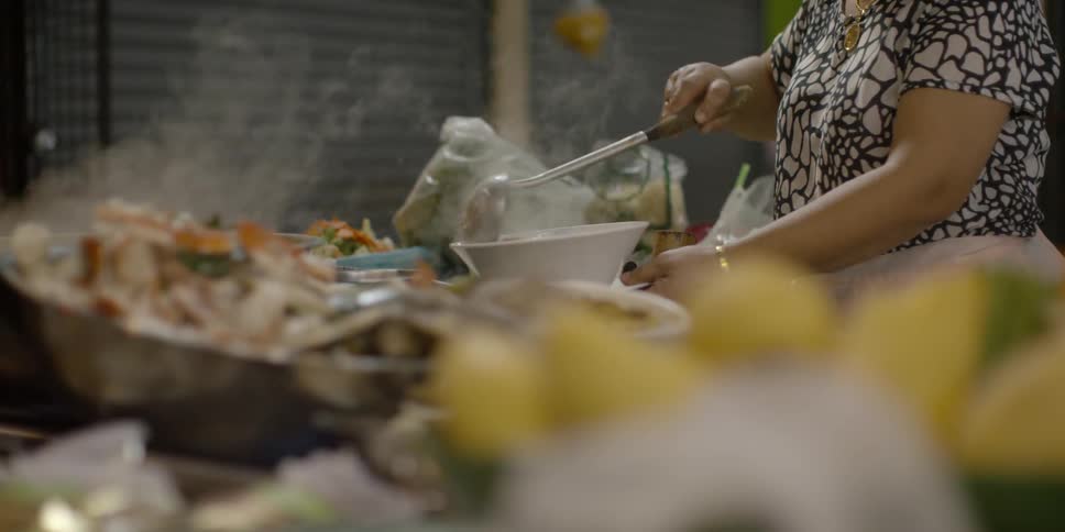 A woman is spooning food into a bowl