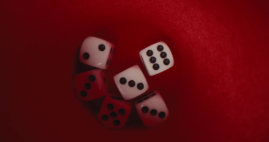 Six white and red dice are inside a red feltlined cup and the camera is from a top view