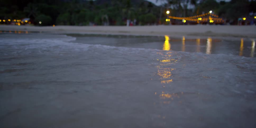 An ocean wave washes ashore a sandy beach