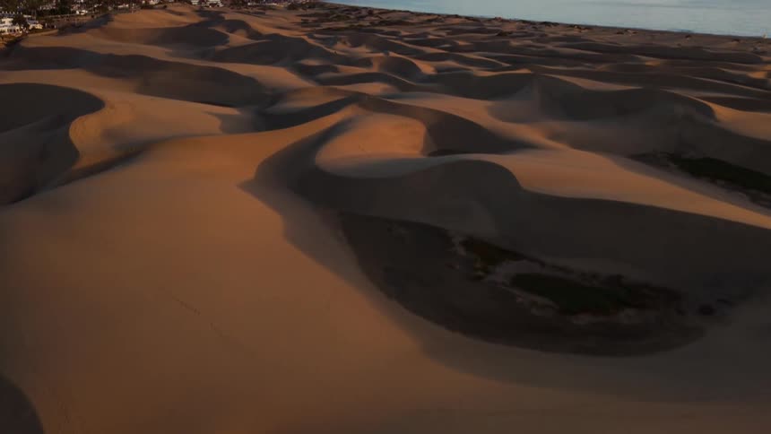 The desert meets the ocean on a sunny day with a town in the background