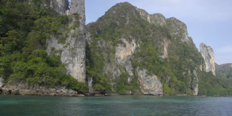 Large rock mountains covered in green bushes next to body of water
