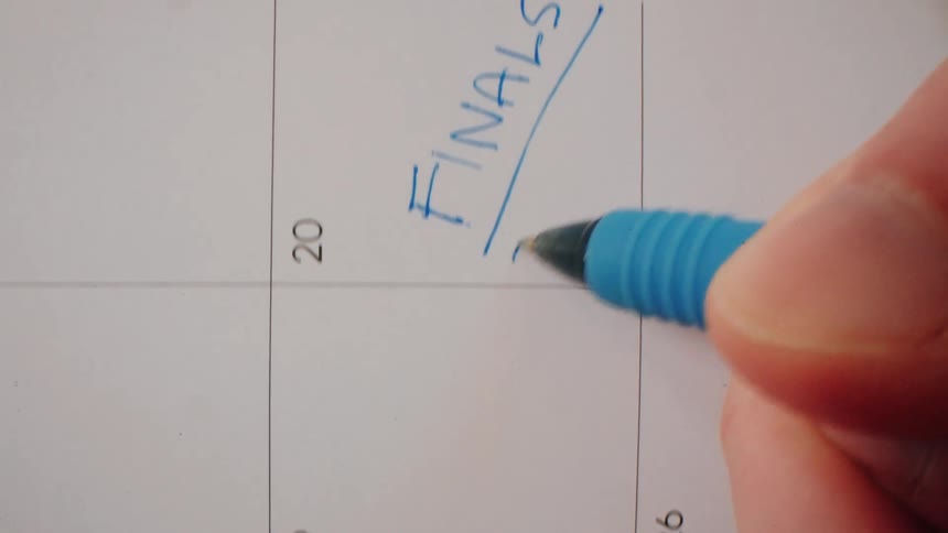 Hand of a person underlying words on a calendar with a pen