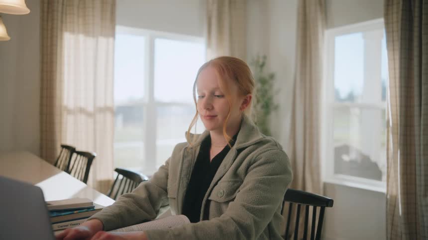 A woman typing on a laptop in a room