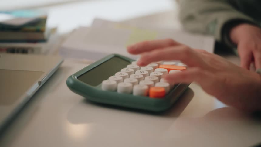 Closeup of a hand pressing buttons on a modern calculator at a desk