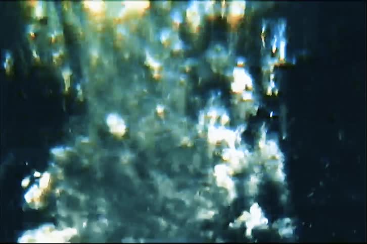 Sparkling water flows into a glass creating rising bubbles