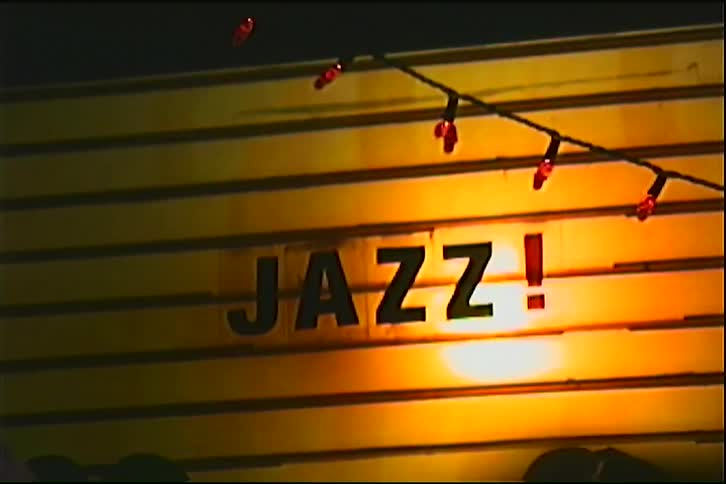 Illuminated sign displaying the word jazz in an indoor venue decorated with lights