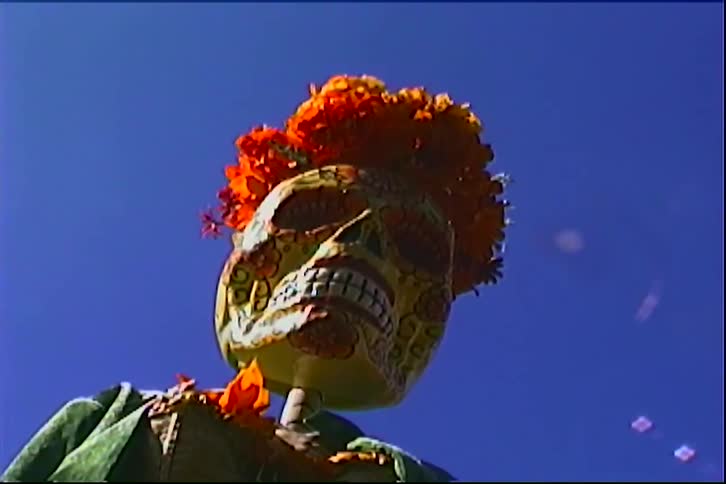 Flowers top a colorfully decorated skeleton wearing a jacket and skirt