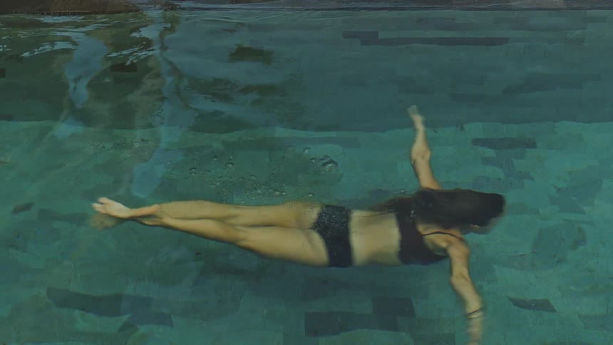 A woman swimming under water in a pool