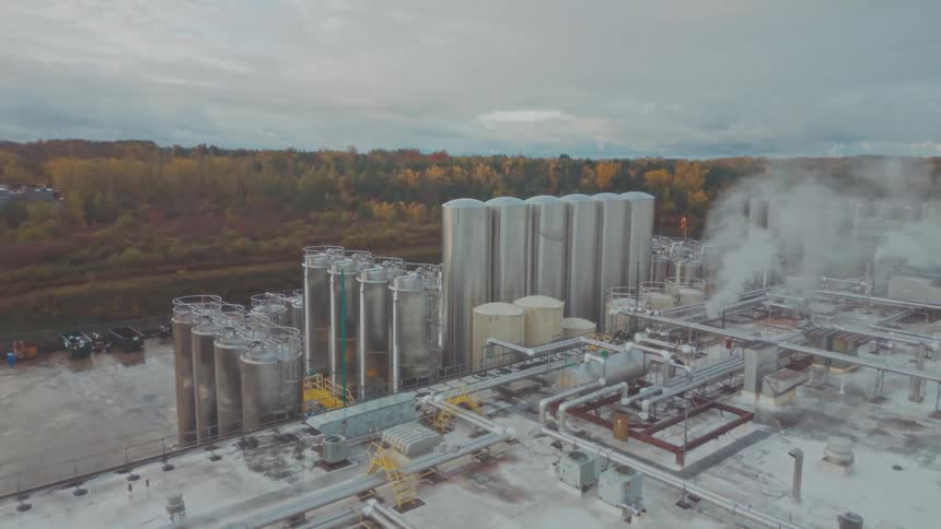 A factory at midday with steam rising from its chimney