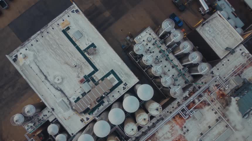 Truck drives by tanks and pipes around an industrial building