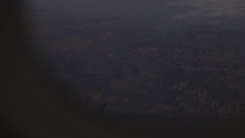 Aerial view of mountainous terrain partially covered by haze under low light