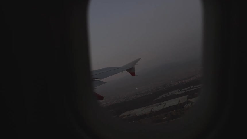 An airplanes wing seen from the window as it takes off in the evening