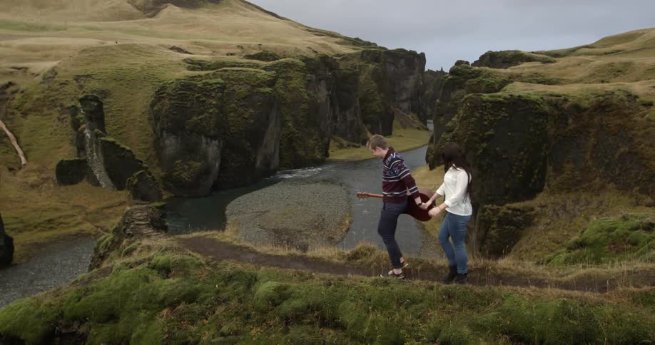 A man with a guitar moves down a trail leading a woman