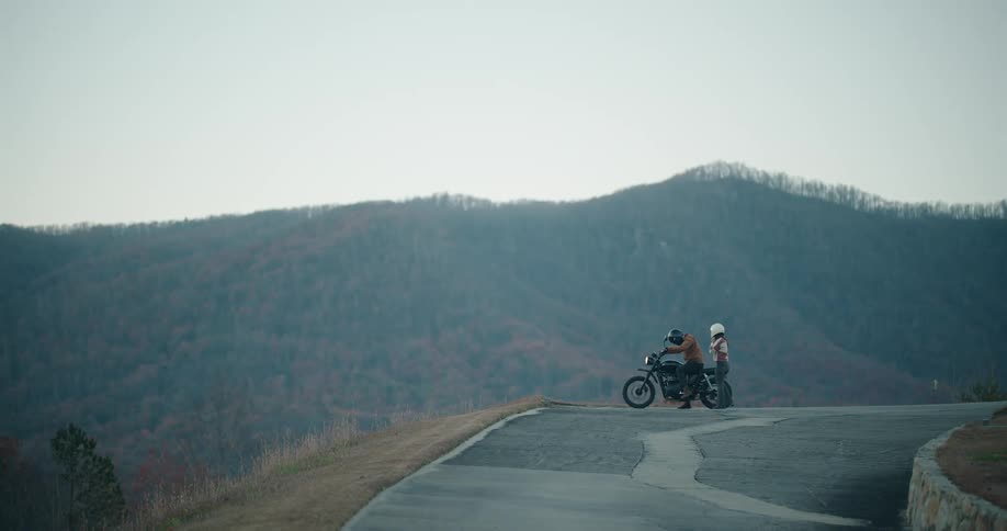 Person parking motorcycle with a mountain landscape
