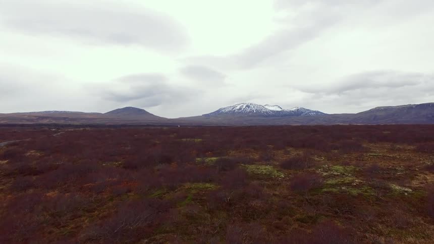 Aerial view of a large field with mountains in the distance on a cloudy day