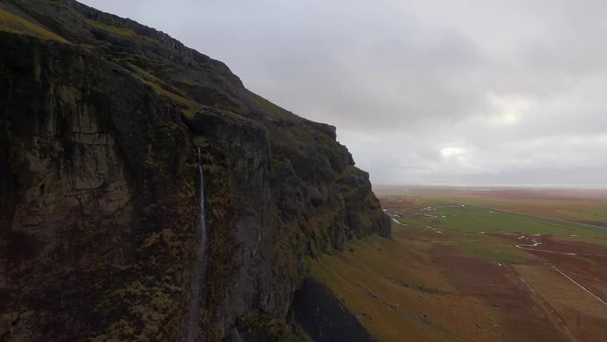 Side of a cliff overlooking plains on a cloudy day