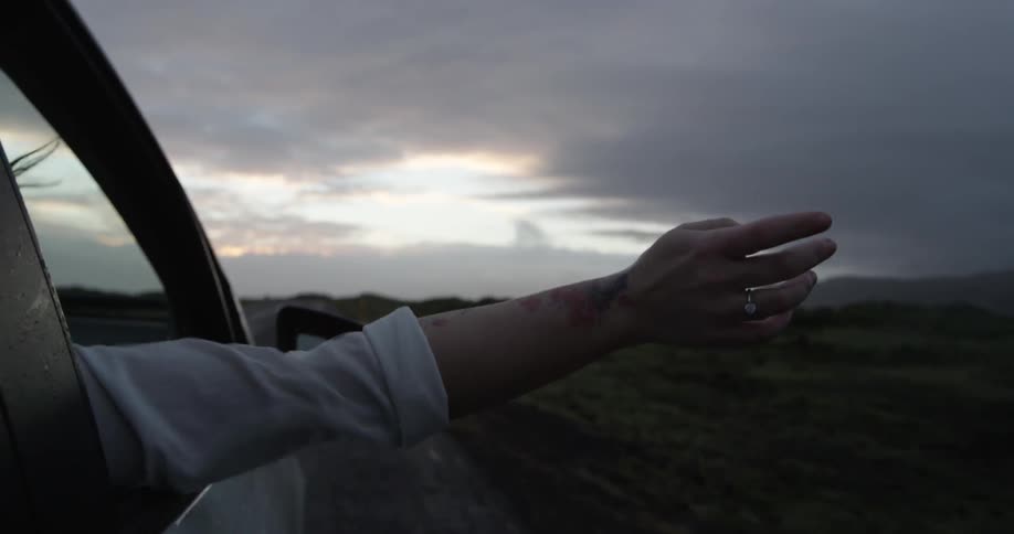 Person waves arm outside of a vehicle on a cloudy day
