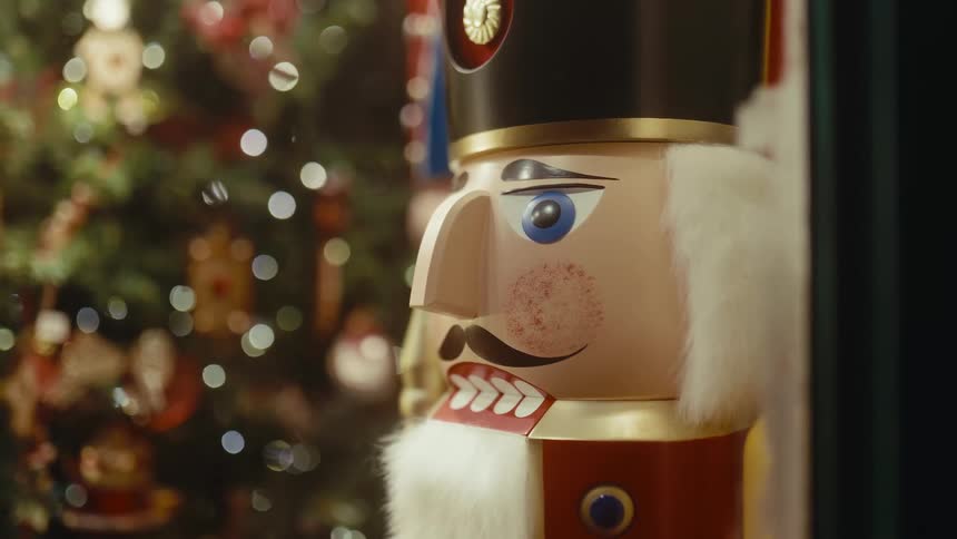 A nutcracker doll standing beside a christmas tree inside a living room