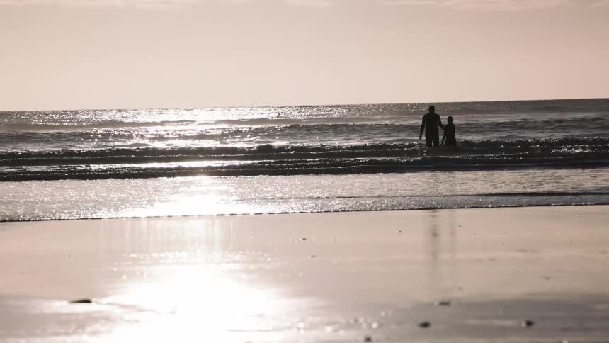 Silhouette of two people enjoying the sea on the beach