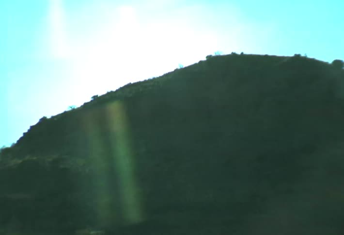 An undeveloped landscape is visible from the window of a vehicle