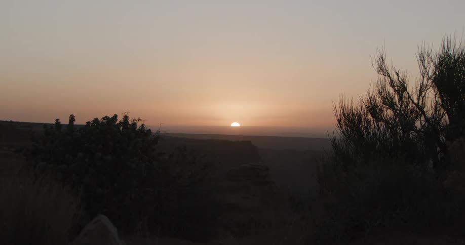 Sun sits on the red horizon while fog covers the nearby canyon