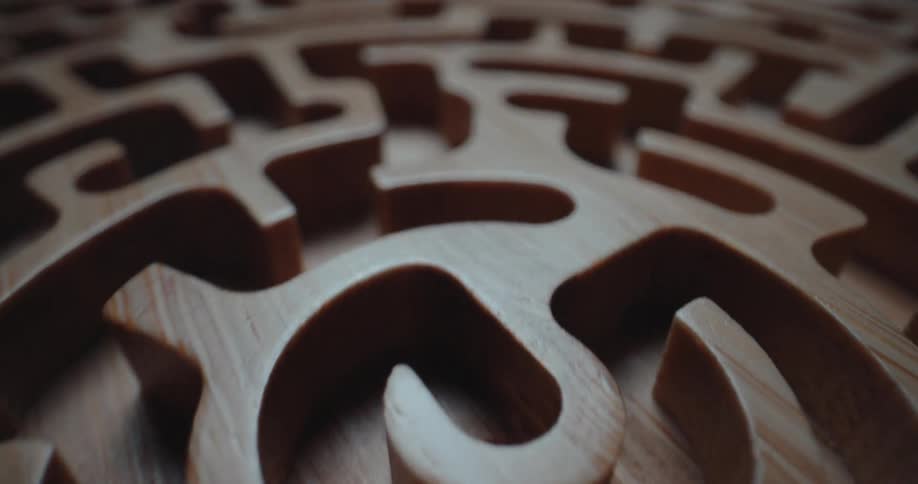 Detail of a circular light wooden maze with curved channels and smooth finish