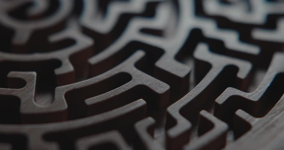 Detail of a dark wooden circular maze with carved channels