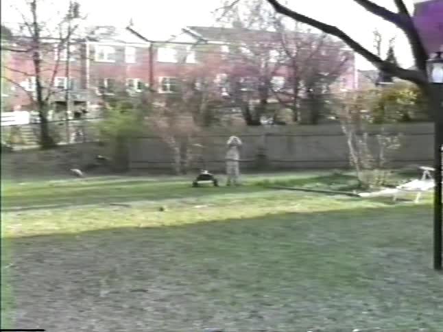 A father plays football in the side yard with his sons on an early spring day