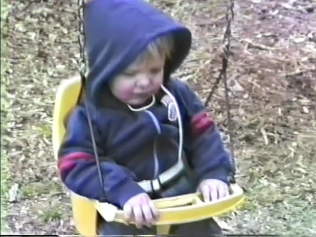 Children playing on a swing set in autumn include a pair sharing a swing
